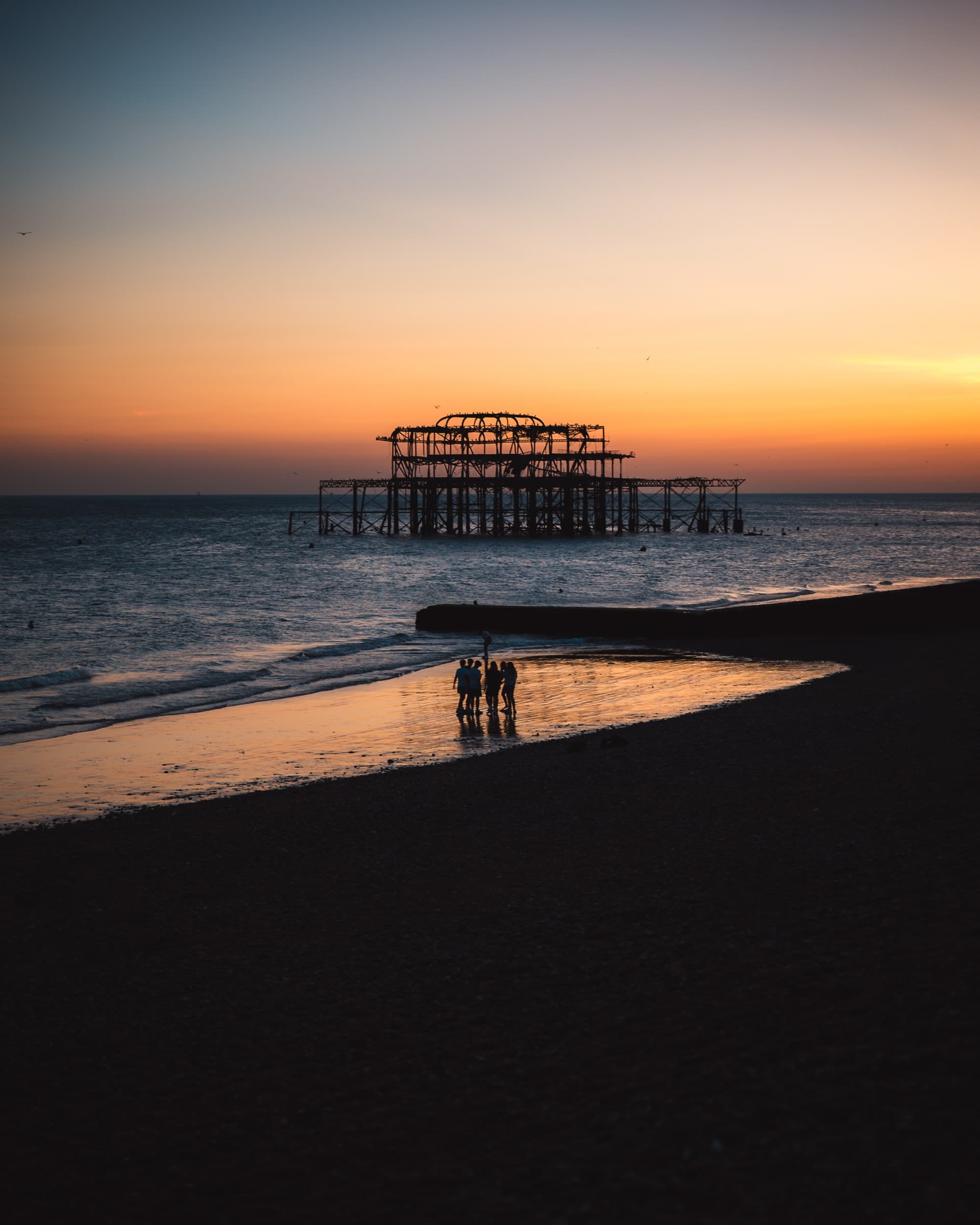 Silhouettes on the beach in front of the West Pier
